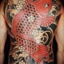 Japanese style back piece tattoo of koi fish in red with black dots on black and grey waves with white cherry blossom leaves