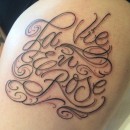 script tattoo on thigh saying la vie en rose