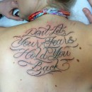 script tattoo on womans back saying don’t let your fears hold you back