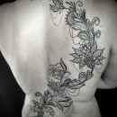 mandala lotus flowers tattoo coming up womans back in black and grey