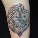 hand picked tattoo of sailing ship in rope frame with rocks and clouds