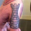 large black and grey rook chess piece on a mans thumb
