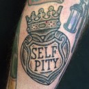 heart locket tattoo with crown that says self pity on the locket