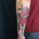 stick poke tattoo of traditional style roses on forearm